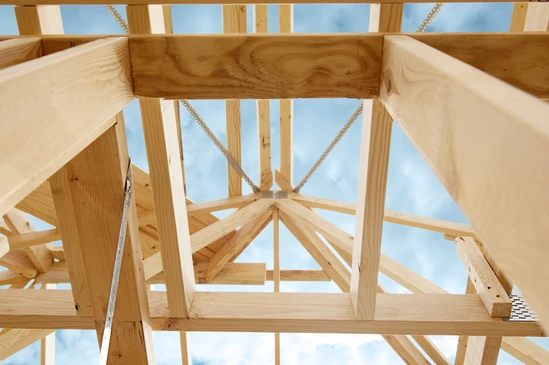 Intérieur d'un bâtiment rénové présentant une charpente traditionnelle apparente avec poutres en bois massif et fermes triangulaires