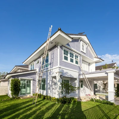 Ouvriers effectuant des travaux de couverture sur une maison moderne à deux étages avec bardage gris et blanc